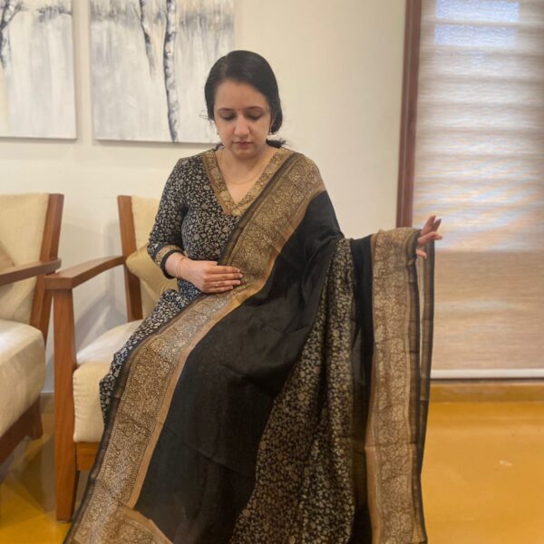 A stunningly gorgeous hand made pure Maheshwari silk set in a beautiful blend of Jet Black & Woodish Gold tone with exquisite & tiny floral block prints & elegant borders that can be used for styling. Santoon bottom Styling tip : We have highlighted the borders using antique gold embroidery & hand made a trending v neck creating a stylish & super elegant attire . You can also style it with simple necks & collars